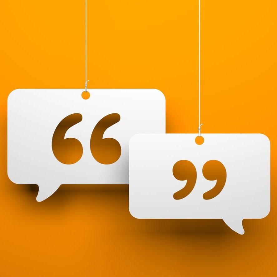 Two white speech bubbles with quotation marks hanging from strings.